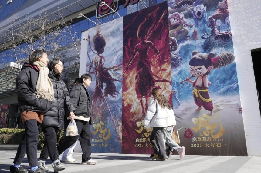 People walk by an advert in Beijing for the animated blockbuster Ne Zha 2 on February 20. Photo: Kyodo